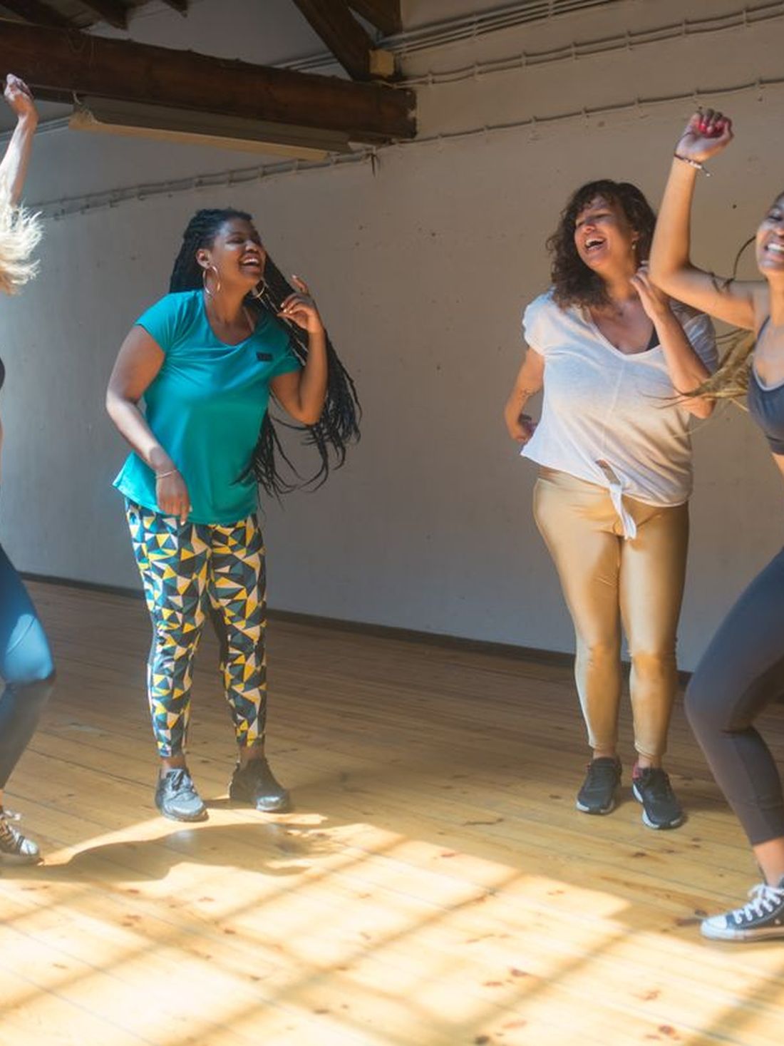 Four women dancing together in a bright studio.