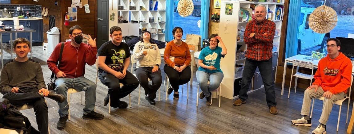 A CreatAbility class seated in a semicircle in the studio, mid-laugh, with an instructor standing at the side.